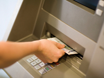 Hand zieht Geldscheine aus einem Geldautomaten.