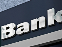 Blauer Hintergrund an Gebäud-Fassade, darauf in silbernen Lettern 'Bank'.