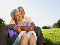 Renter-Ehepaar sitzt glücklich auf einer Wiese.